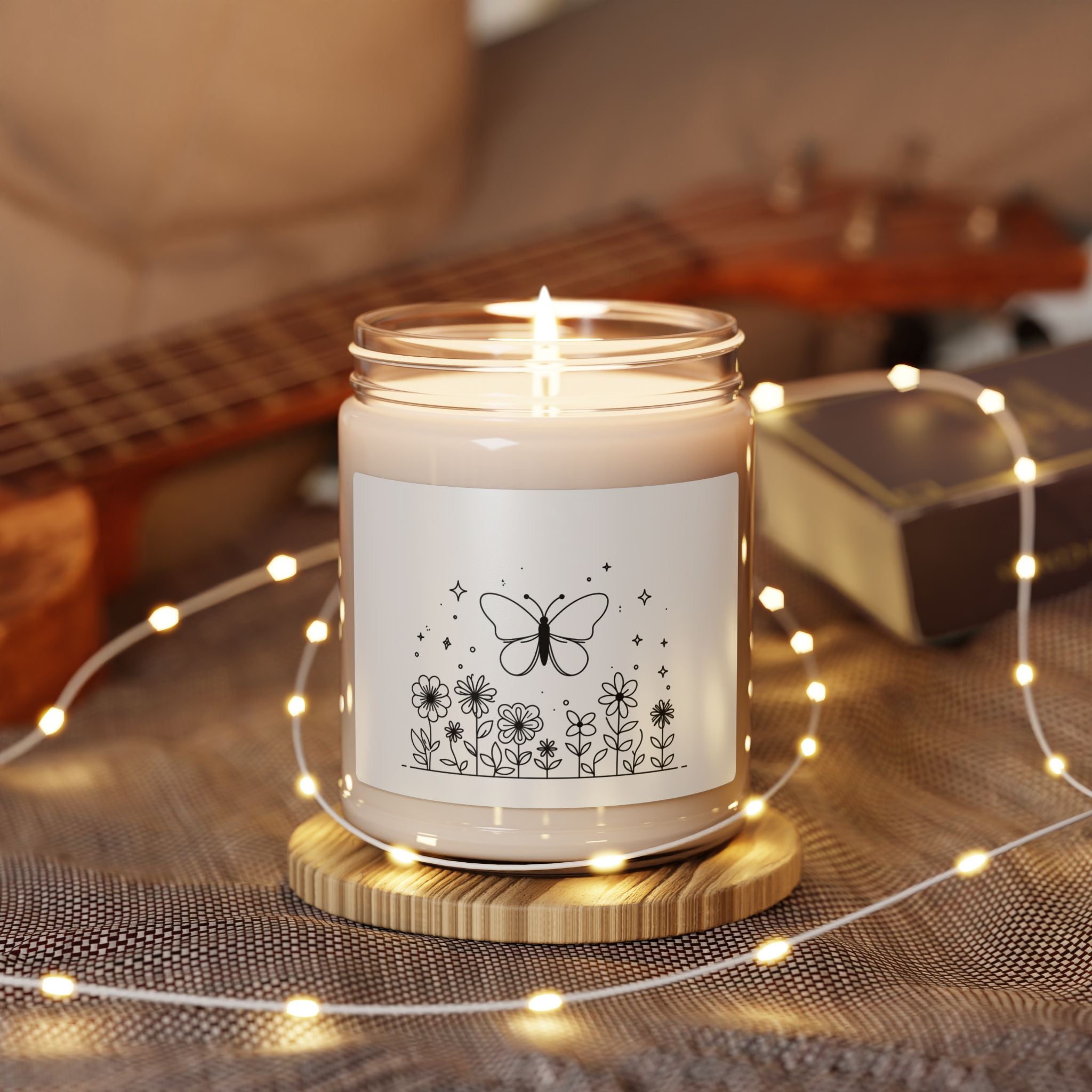 This scented candle is a black-and-white illustration features a whimsical butterfly hovering above a garden of blooming flowers.