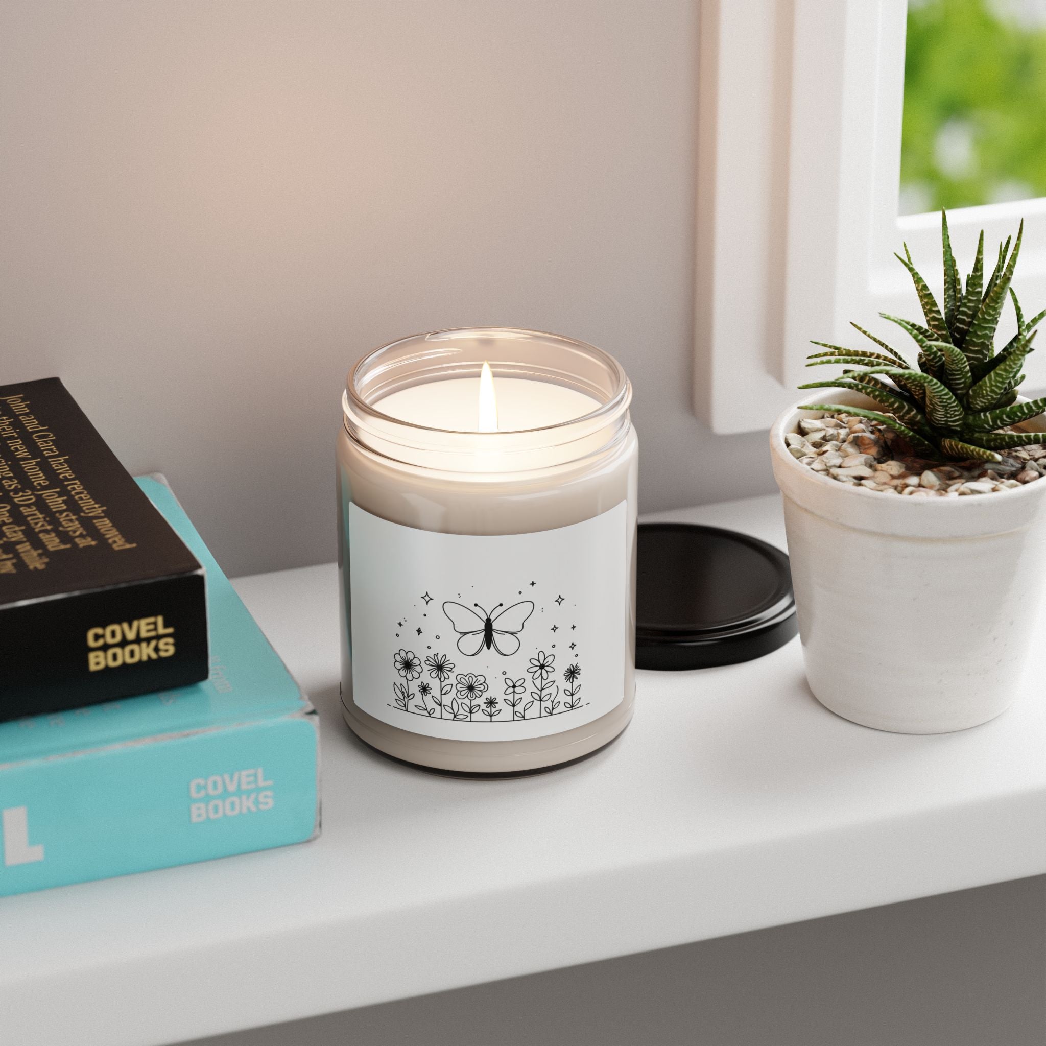 This scented candle is a black-and-white illustration features a whimsical butterfly hovering above a garden of blooming flowers.