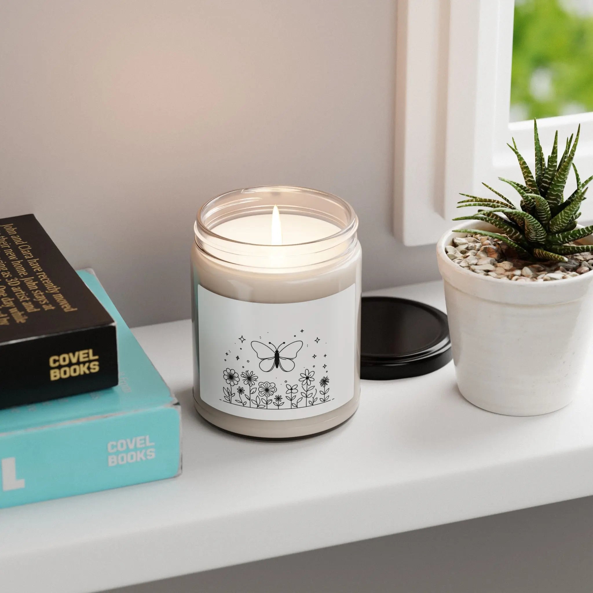This scented candle is a black-and-white illustration features a whimsical butterfly hovering above a garden of blooming flowers. Printify